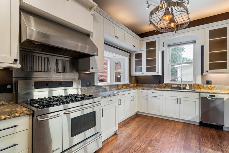 Spacious kitchen with stainless steel appliances, granite countertops, and wooden flooring.